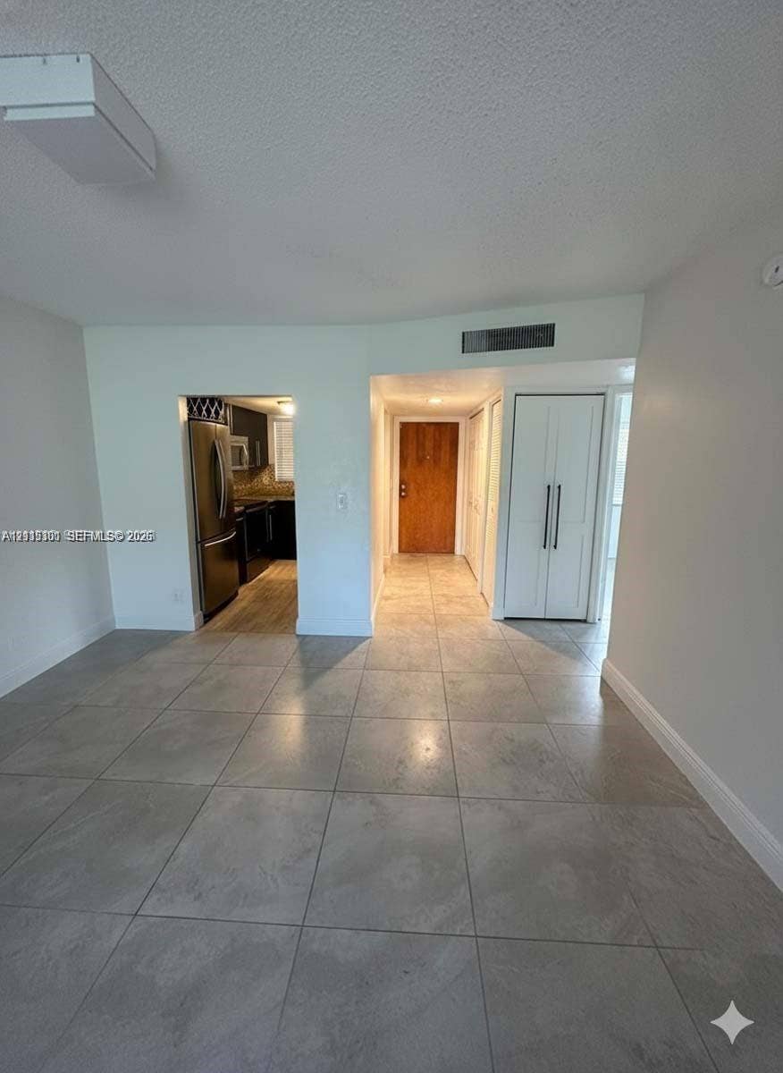 1630 Embassy Drive, #101, West Palm Beach, West Palm Beach, FL 33401 Large-format ceramic tile flooring, solid wood-finish entry door, built-in double-door closet cabinetry with vertical hardware, and flush-mount rectangular ceiling lighting