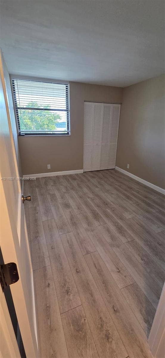 115 Lake Emerald Drive, #408, Oakland Park, FL 33309 Wood-finish flooring, horizontal slat window blinds, and white bifold closet doors