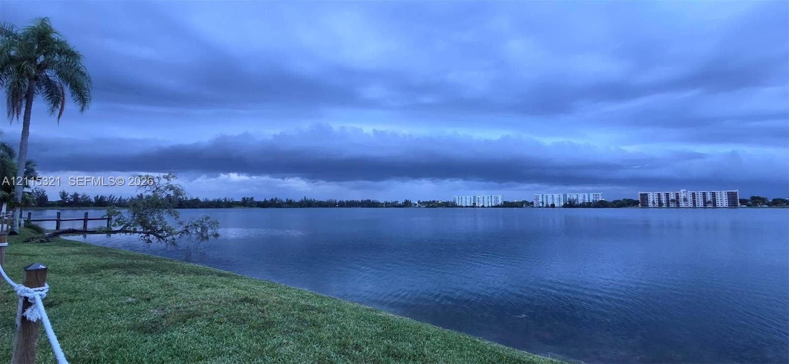 115 Lake Emerald Drive, #408, Oakland Park, FL 33309 Waterfront parcel featuring a manicured grass shoreline, nautical rope perimeter fencing, and mature palm trees