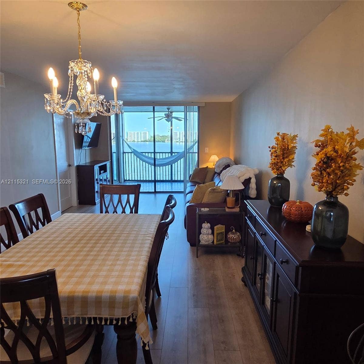 115 Lake Emerald Drive, #408, Oakland Park, FL 33309 Open-concept interior featuring wood-finish flooring, a multi-arm crystal chandelier, and a screened-in balcony with water scenery