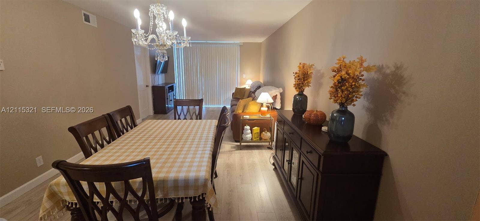 115 Lake Emerald Drive, #408, Oakland Park, FL 33309 Light-toned wood-finish flooring, crystal chandelier, and sliding glass door with vertical blinds