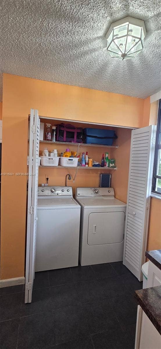 115 Lake Emerald Drive, #408, Oakland Park, FL 33309 Laundry alcove featuring white louvered bifold doors, integrated metal shelving, and dark tile flooring