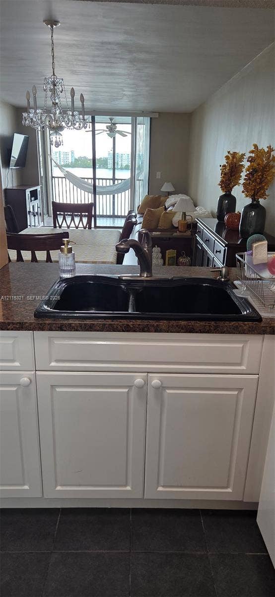 115 Lake Emerald Drive, #408, Oakland Park, FL 33309 Kitchen featuring white shaker-style cabinetry, dark stone-finish countertops, and an integrated dual-basin sink with a metallic pull-down faucet