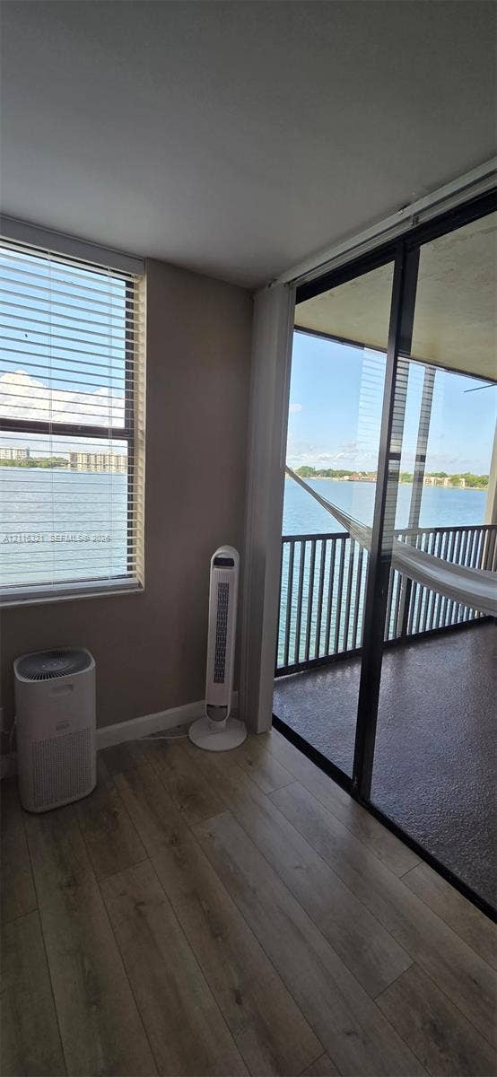 115 Lake Emerald Drive, #408, Oakland Park, FL 33309 Wood-finish flooring, floor-to-ceiling windows, sliding glass door, and covered balcony with metal railing overlooking the water