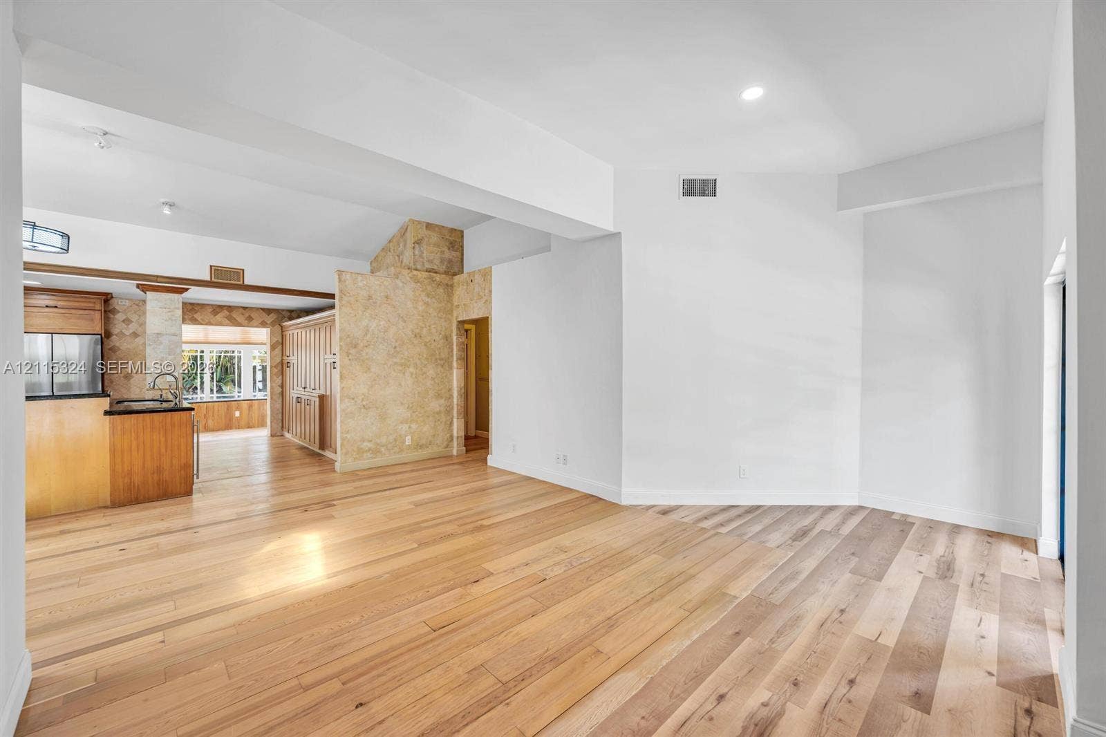 Open floor plan featuring wood-finish flooring, recessed lighting, and a neutral color palette with textured stone-finish accent walls