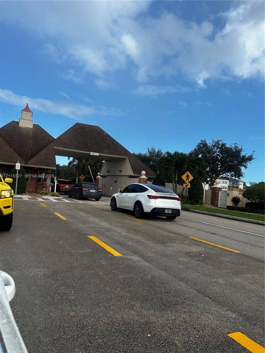 335 Brighton H, #H, Boca Raton, Boca Raton, FL 33434 Gated entrance featuring a brick-accented guard house with a shingled roof structure