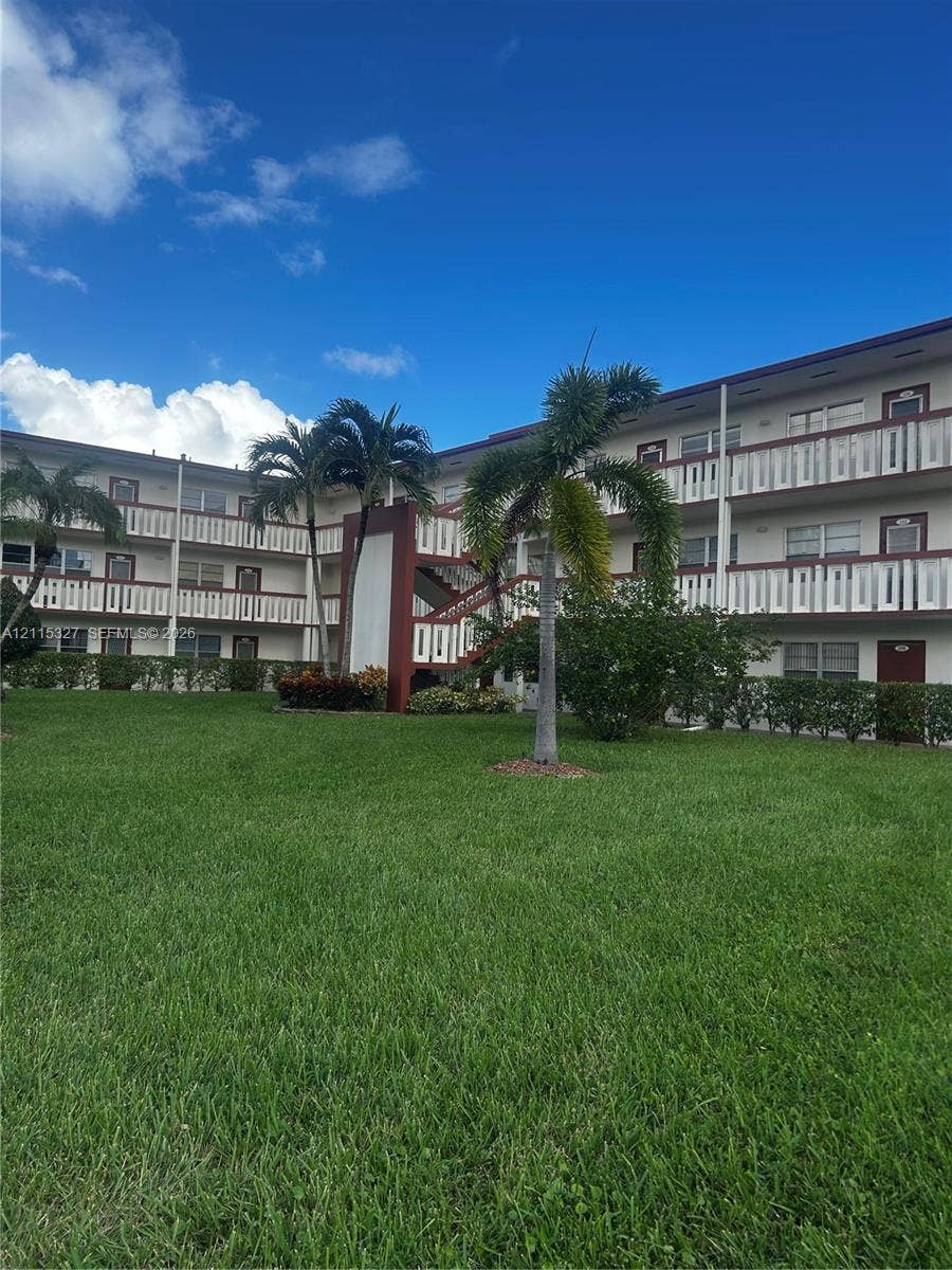 335 Brighton H, #H, Boca Raton, Boca Raton, FL 33434 Multi-story exterior featuring white balconies, dark-framed sliding windows, integrated staircases, and surrounding palm trees
