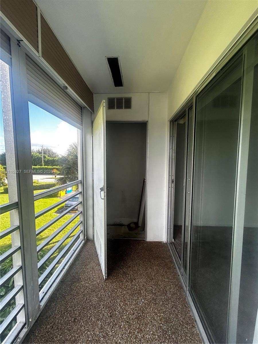 335 Brighton H, #H, Boca Raton, Boca Raton, FL 33434 Enclosed balcony featuring a pebble-finish floor, floor-to-ceiling metal-framed windows, and a swinging utility door