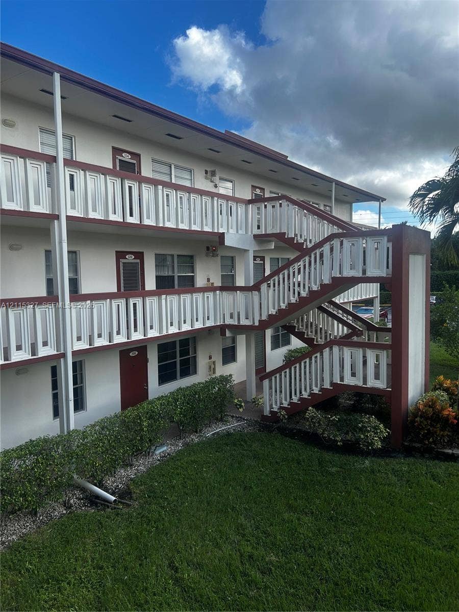 335 Brighton H, #H, Boca Raton, Boca Raton, FL 33434 Multi-story exterior featuring white stucco siding, contrasting trim, white decorative railings, and an integrated outdoor staircase