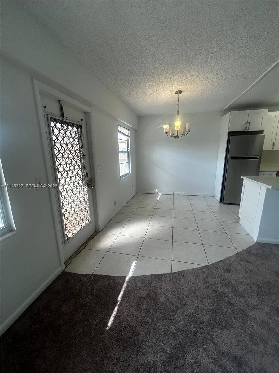 335 Brighton H, #H, Boca Raton, Boca Raton, FL 33434 Neutral-toned ceramic tile flooring, white shaker-style cabinetry, stainless steel refrigerator, and multi-arm chandelier lighting