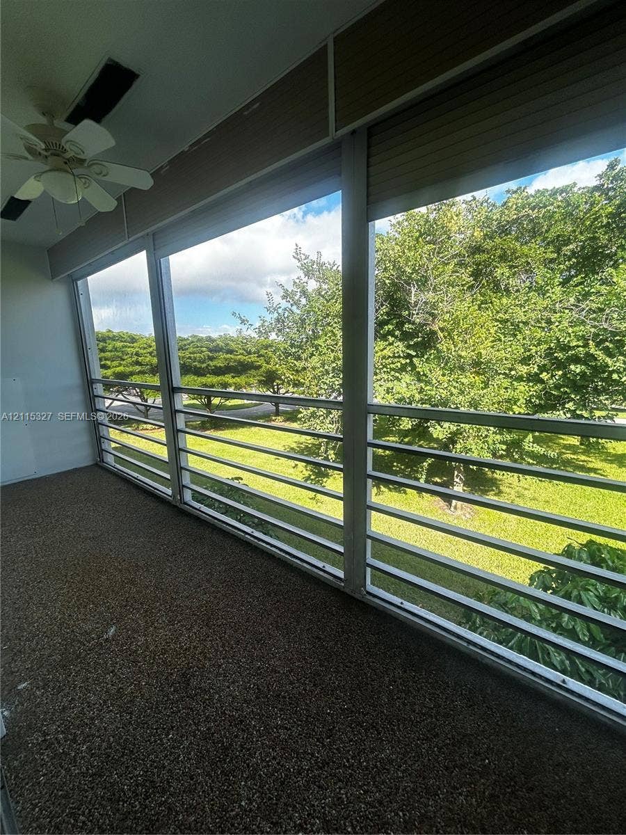 335 Brighton H, #H, Boca Raton, Boca Raton, FL 33434 Covered balcony featuring aggregate flooring, horizontal metal railing, integrated ceiling fan, and retractable exterior shades