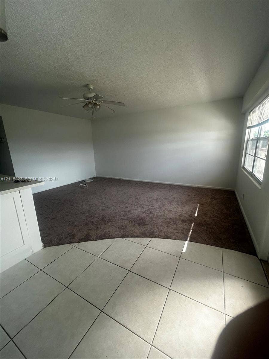 335 Brighton H, #H, Boca Raton, Boca Raton, FL 33434 Spacious interior featuring large-format tile flooring, plush wall-to-wall carpeting, ceiling fan with light fixture, and large paneled windows