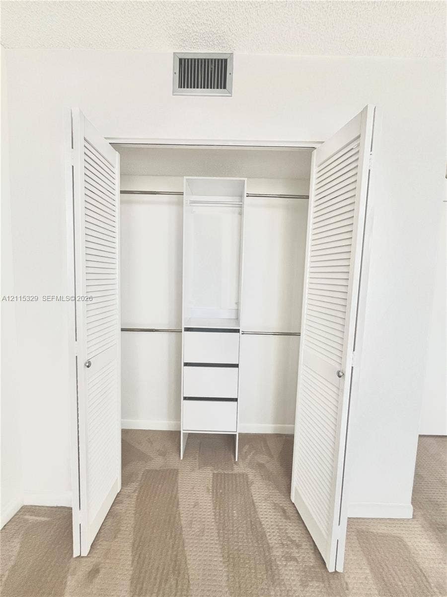 2500 Parkview Drive, #1705, Hallandale Beach, Hallandale Beach, FL 33009 Closet featuring white louvered doors, built-in shelving with three integrated drawers, and dual hanging rods