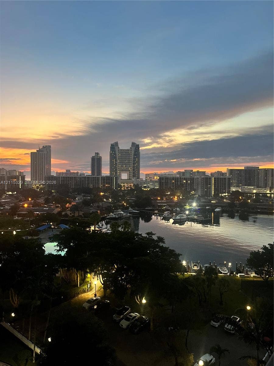 2500 Parkview Drive, #1705, Hallandale Beach, Hallandale Beach, FL 33009 Panoramic cityscape featuring high-rise buildings, a waterfront marina, and mature landscaping under a sunset sky