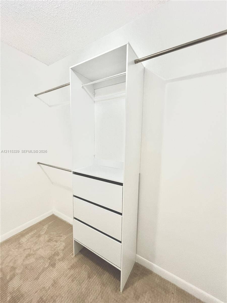 2500 Parkview Drive, #1705, Hallandale Beach, Hallandale Beach, FL 33009 Walk-in closet featuring white built-in cabinetry, three drawers, an open shelving compartment, and metal clothing rods