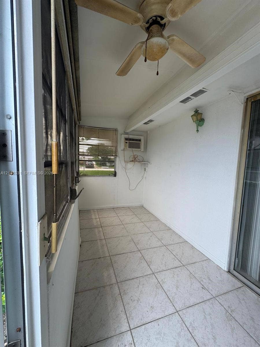 22 Valencia A, Delray Beach, FL 33446 Enclosed sunroom featuring large-format ceramic tile flooring, a ceiling fan with integrated light fixture, a wall-mounted light, and screened window enclosures