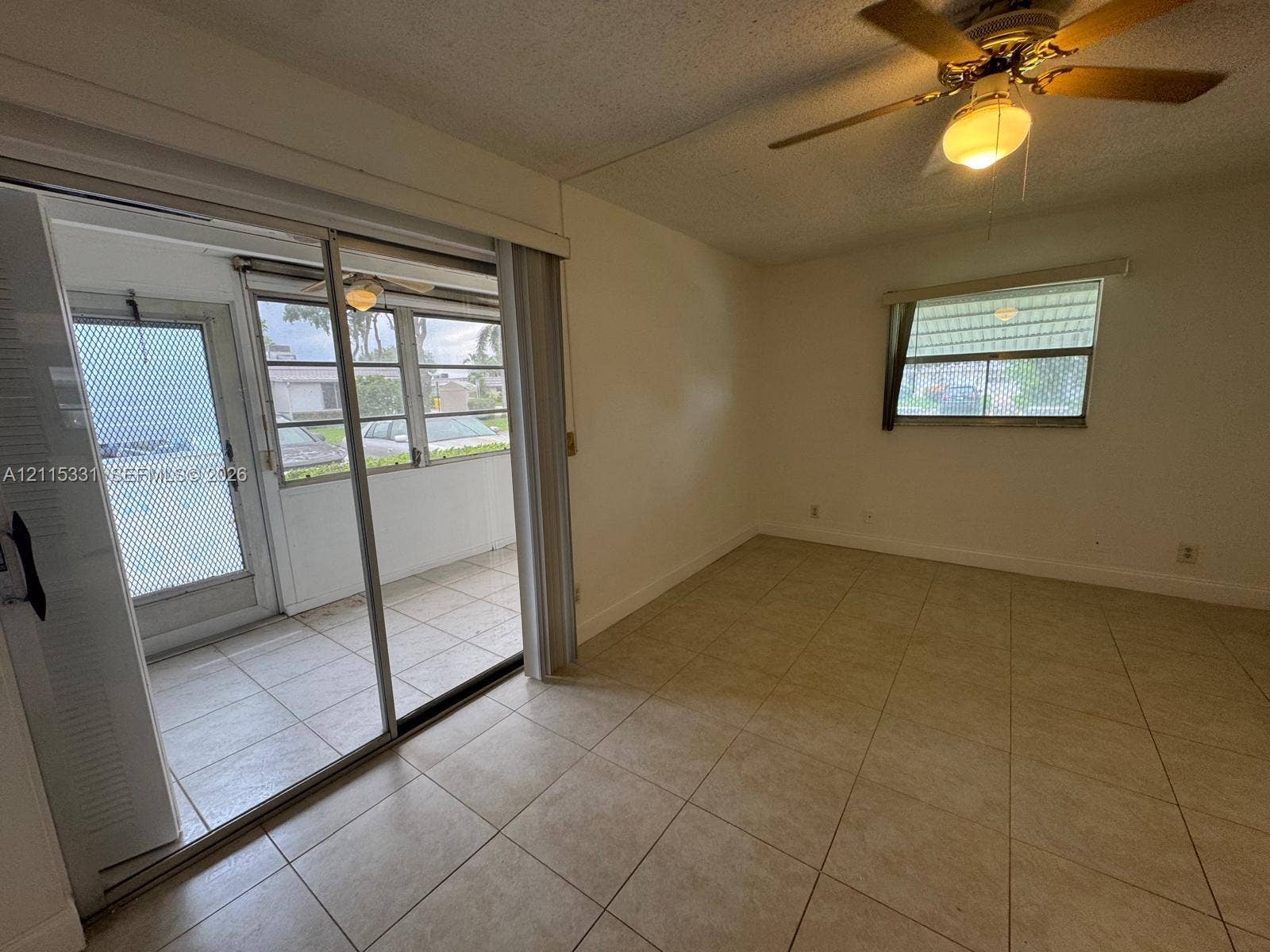 22 Valencia A, Delray Beach, FL 33446 Ceramic tile flooring, sliding glass sunroom doors, ceiling-mounted light fixture with fan, and screened-in porch with tiled flooring