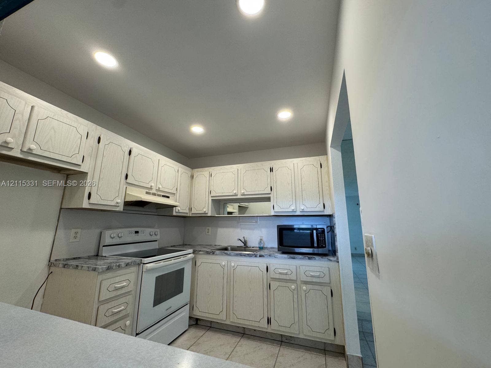 22 Valencia A, Delray Beach, FL 33446 Kitchen featuring cabinetry with routed detailing, laminate countertops, recessed ceiling lighting, and tile flooring