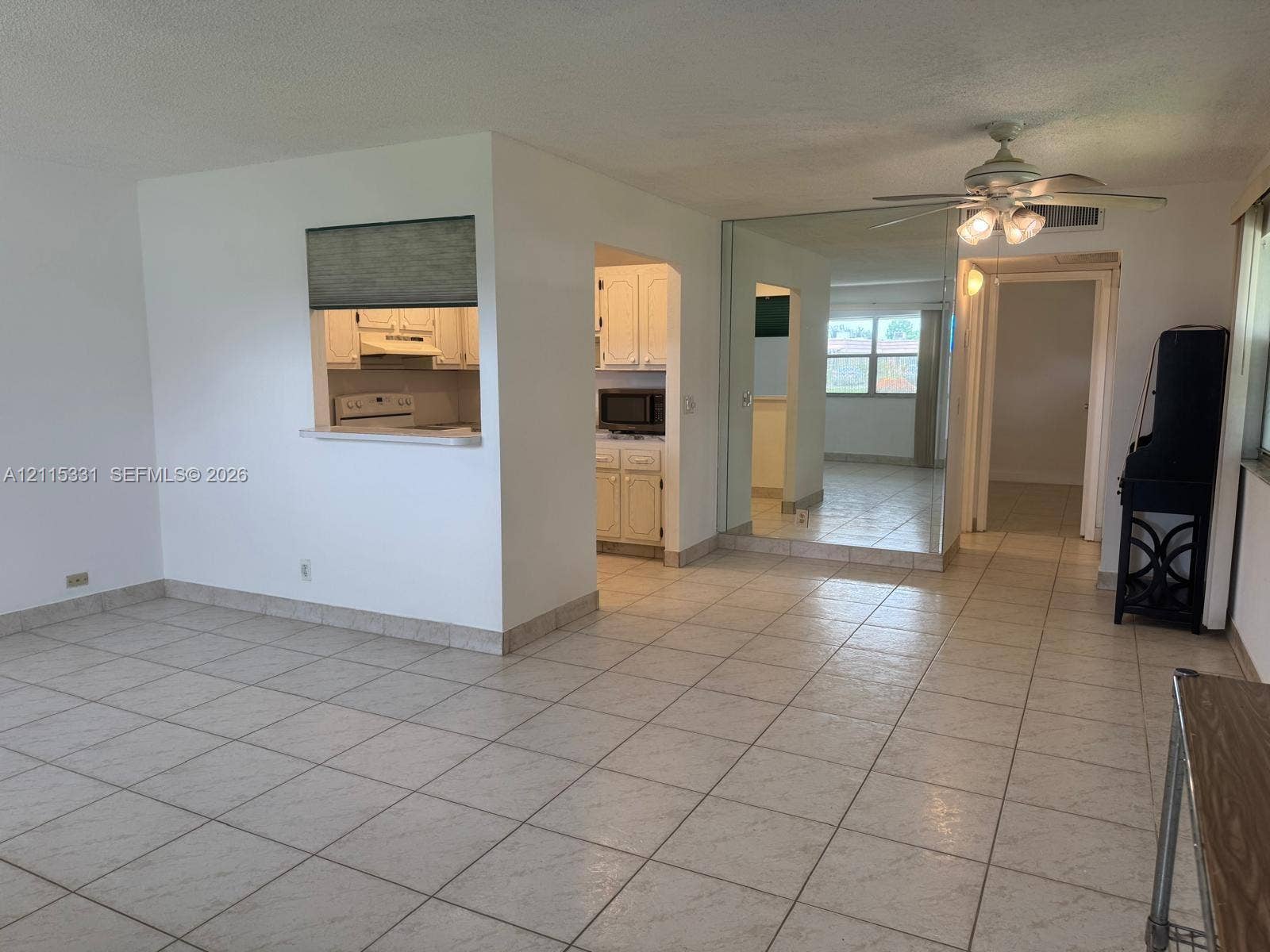 22 Valencia A, Delray Beach, FL 33446 Ceramic tile flooring, mirrored wall paneling, ceiling-mounted light fixture with fan, and interior pass-through window with ledge