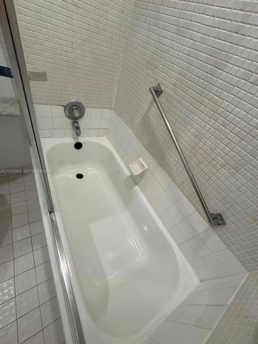 22 Valencia A, Delray Beach, FL 33446 New Bathtub featuring tiled surround, stainless steel hardware, and metal grab bar
