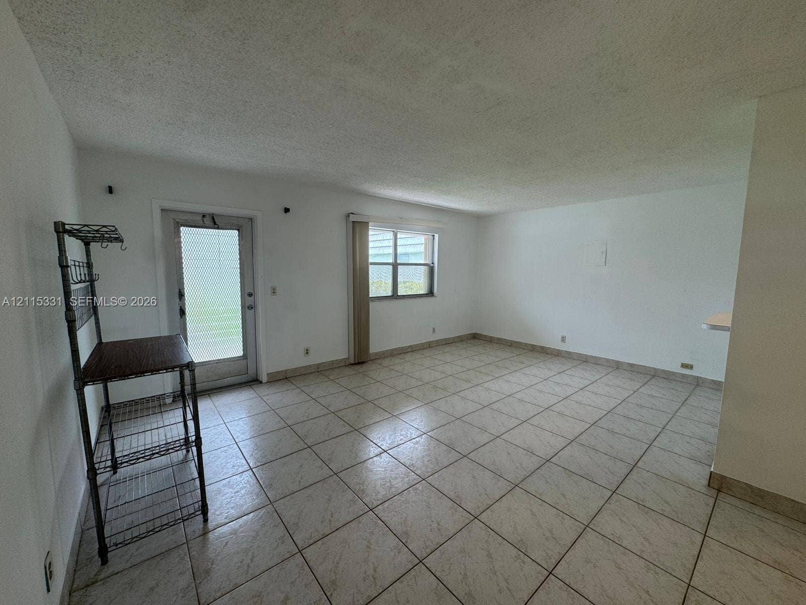 22 Valencia A, Delray Beach, FL 33446 Neutral-toned ceramic tile flooring, textured ceiling finish, exterior door with textured glass inset, and double-pane window
