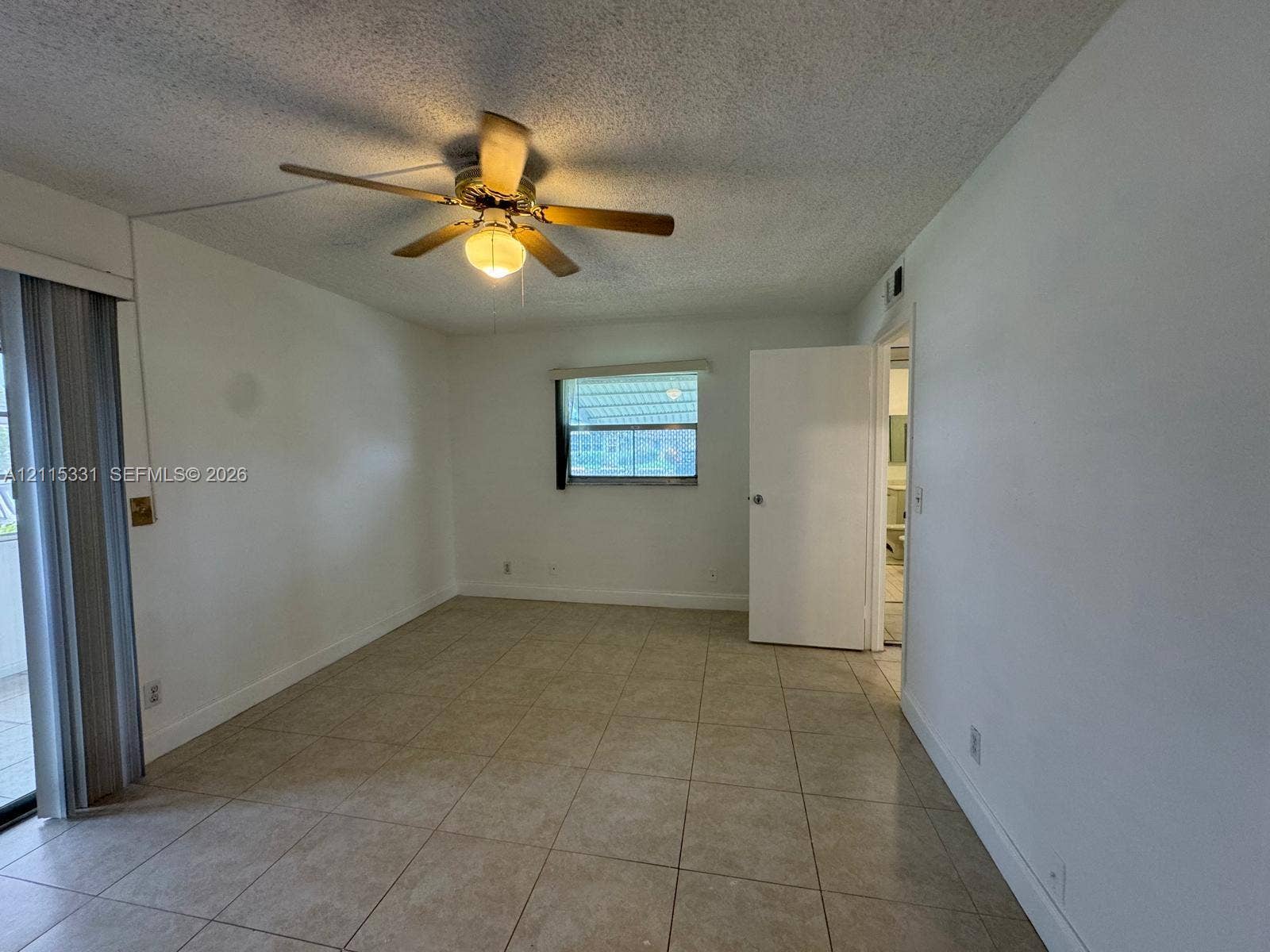 22 Valencia A, Delray Beach, FL 33446 Tile flooring throughout, neutral interior paint, integrated ceiling fan with light fixture, sliding glass door, and window with natural light