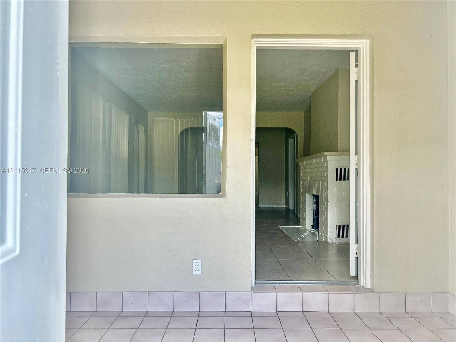 Tiled flooring, large picture window, and interior fireplace with a brick surround