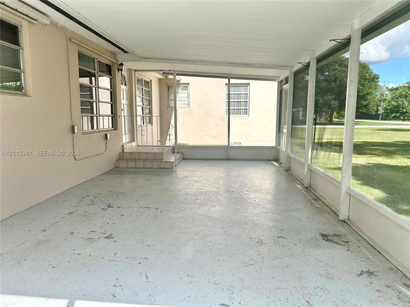 Screened-in patio featuring painted concrete flooring, an overhead cover, and multiple window-paned wall units
