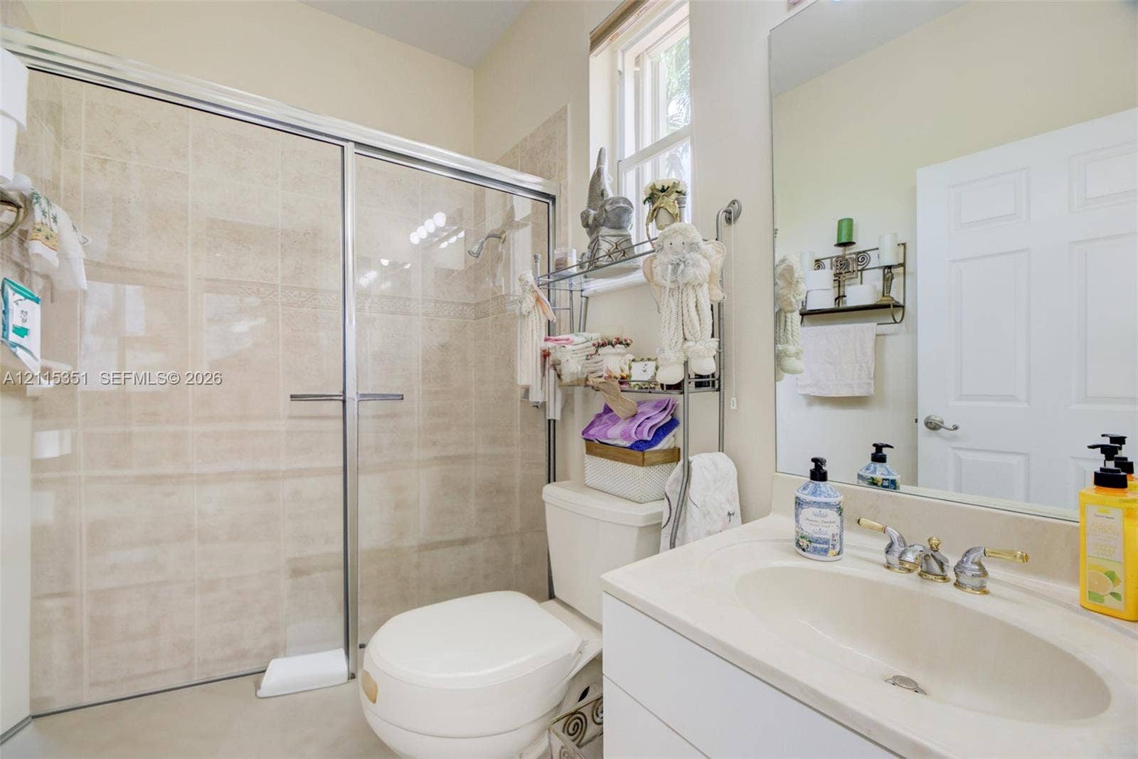 13845 NW 20th Street, Pembroke Pines, FL 33028 Bathroom featuring a shower stall with a glass enclosure, light-toned wall tile, a vanity with an integrated basin, a polished faucet, and a large wall-mounted mirror