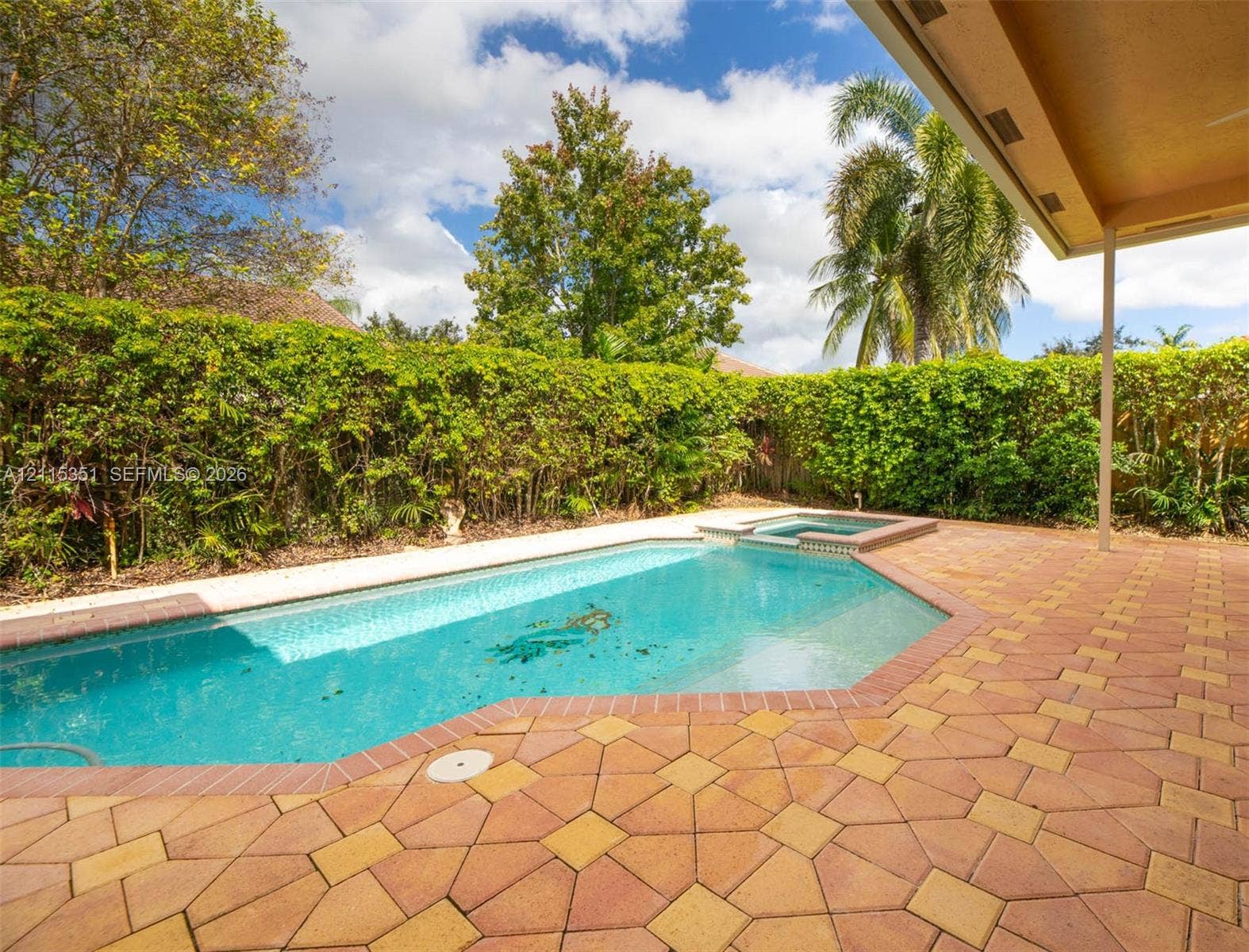 13845 NW 20th Street, Pembroke Pines, FL 33028 Swimming pool with integrated spa, paver patio, covered porch, and mature perimeter hedging