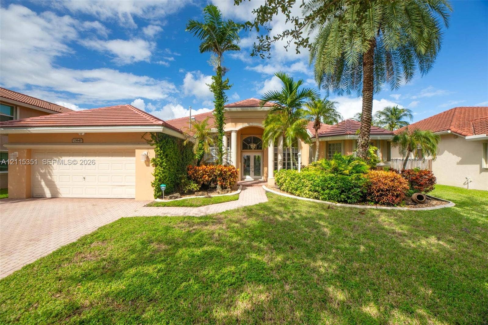13845 NW 20th Street, Pembroke Pines, FL 33028 Stucco exterior featuring a clay tile roof, arched entryway with decorative columns, brick-paver driveway, and mature landscaping