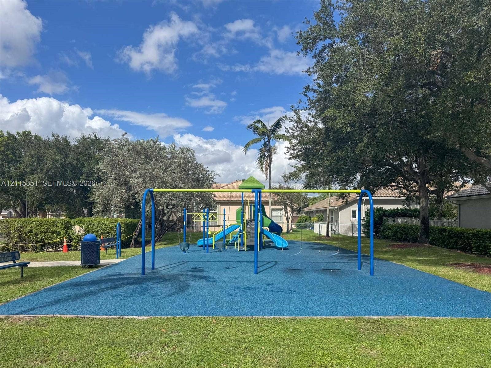 13845 NW 20th Street, Pembroke Pines, FL 33028 Community recreation area featuring a playground structure with slides, swing sets, a poured-in-place rubberized surface, and mature landscaping