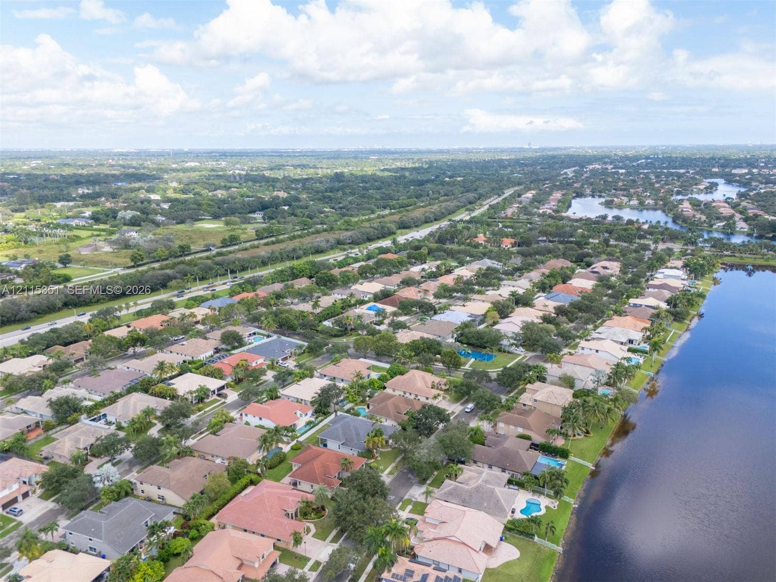 13845 NW 20th Street, Pembroke Pines, FL 33028 Aerial perspective of a residential community featuring extensive waterfront acreage, paved roadways, and dense mature landscaping