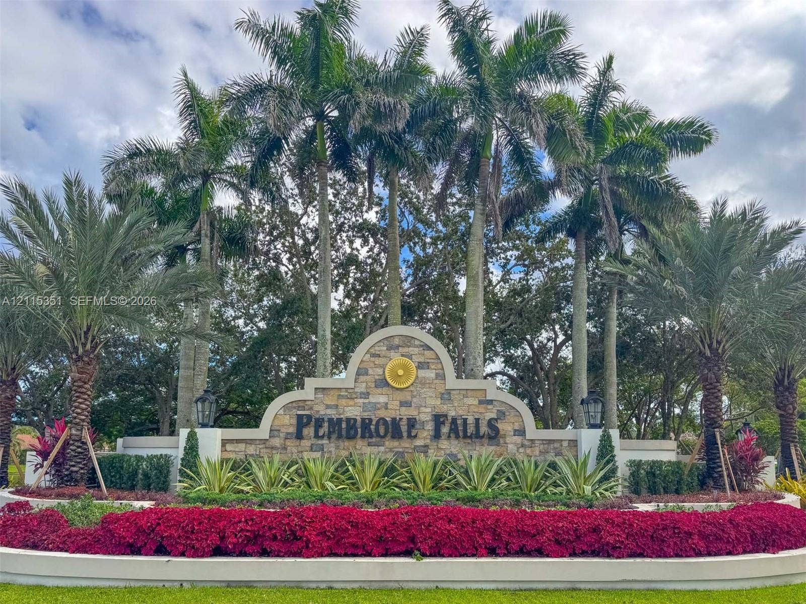 13845 NW 20th Street, Pembroke Pines, FL 33028 Community entrance signage featuring masonry stonework, dual exterior light fixtures, mature palm trees, and tiered landscaping