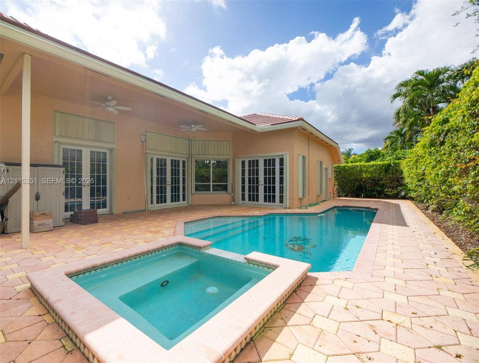 13845 NW 20th Street, Pembroke Pines, FL 33028 Covered patio with stone-paver decking, integrated swimming pool, attached spa, and multi-panel French doors