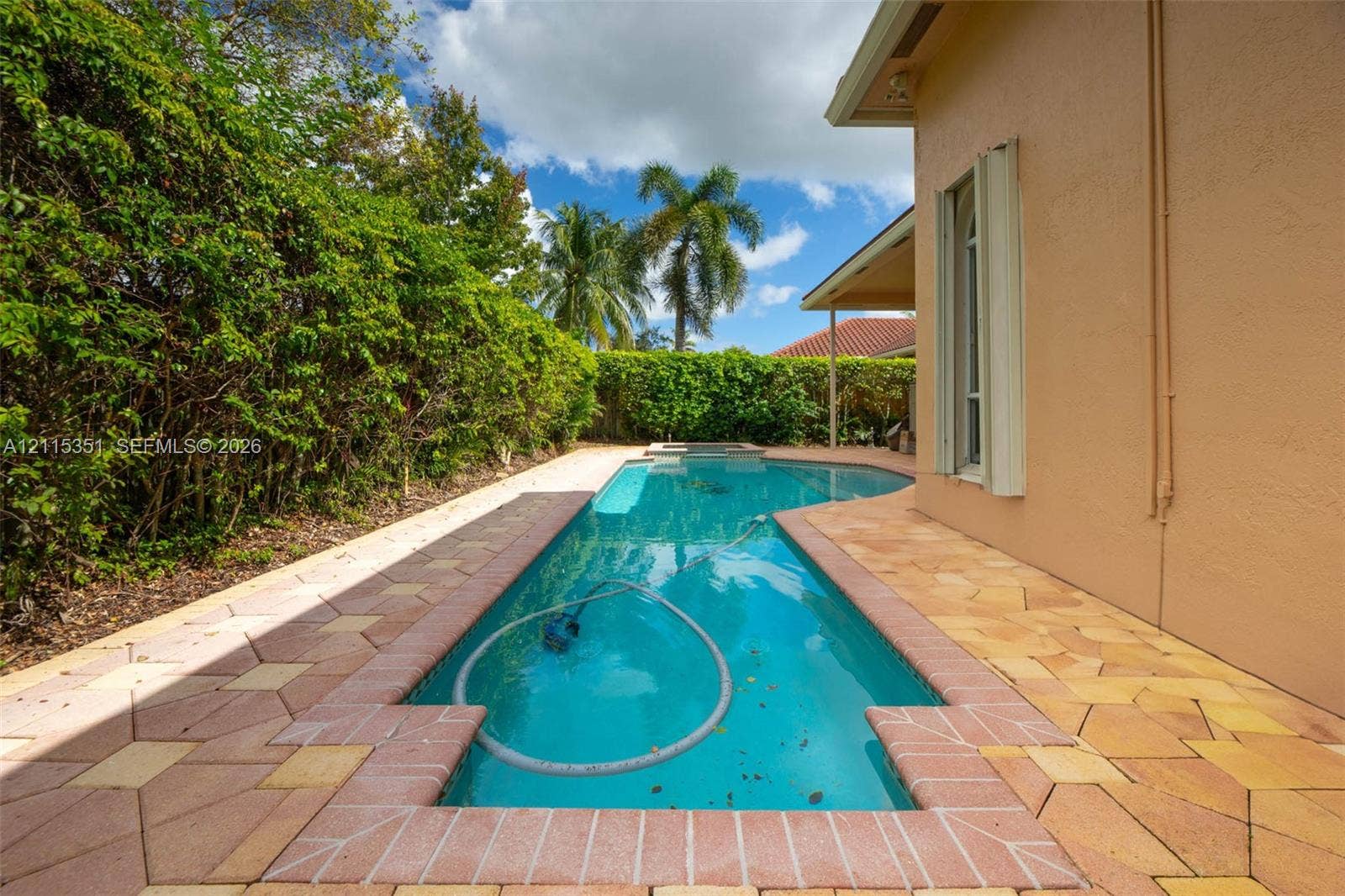 13845 NW 20th Street, Pembroke Pines, FL 33028 In-ground swimming pool surrounded by a multi-tonal paver deck, accented by mature perimeter hedge landscaping and a covered patio area