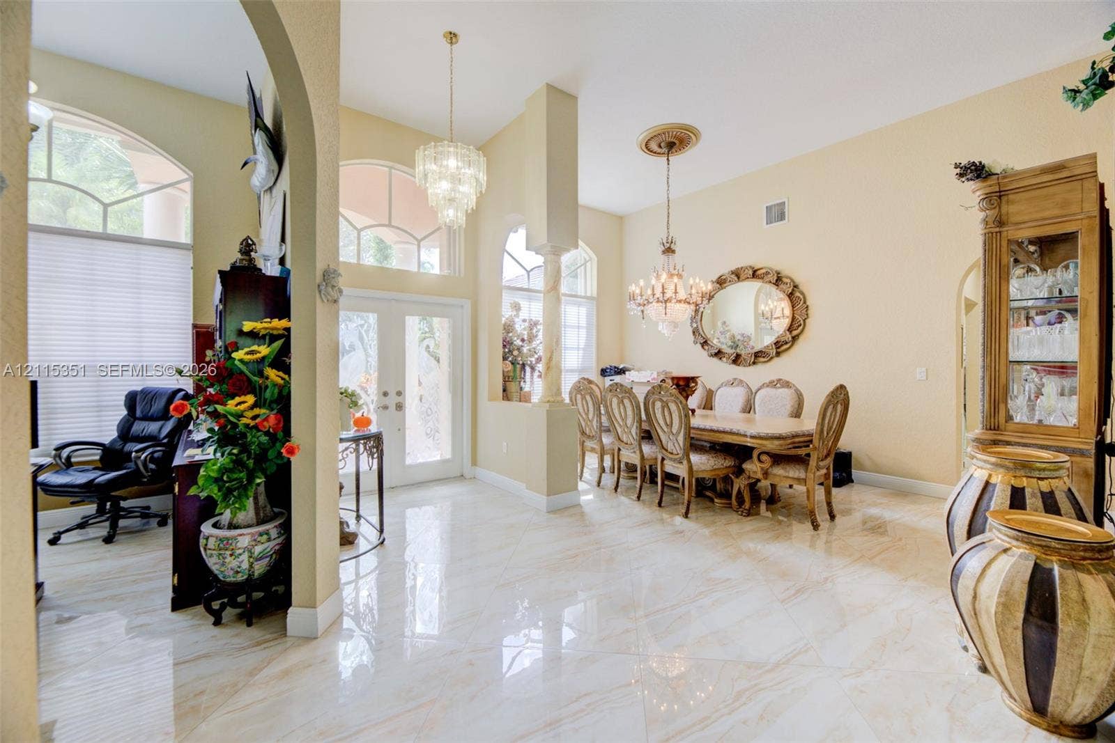 13845 NW 20th Street, Pembroke Pines, FL 33028 High-ceiling foyer featuring polished tile flooring, arched entryways, decorative columns, and dual crystal chandeliers