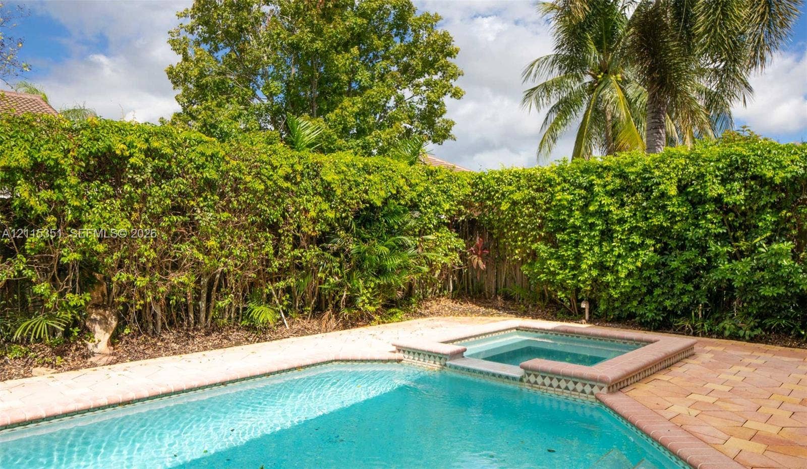 13845 NW 20th Street, Pembroke Pines, FL 33028 Swimming pool with attached spa, concrete paver decking, and dense perimeter landscaping