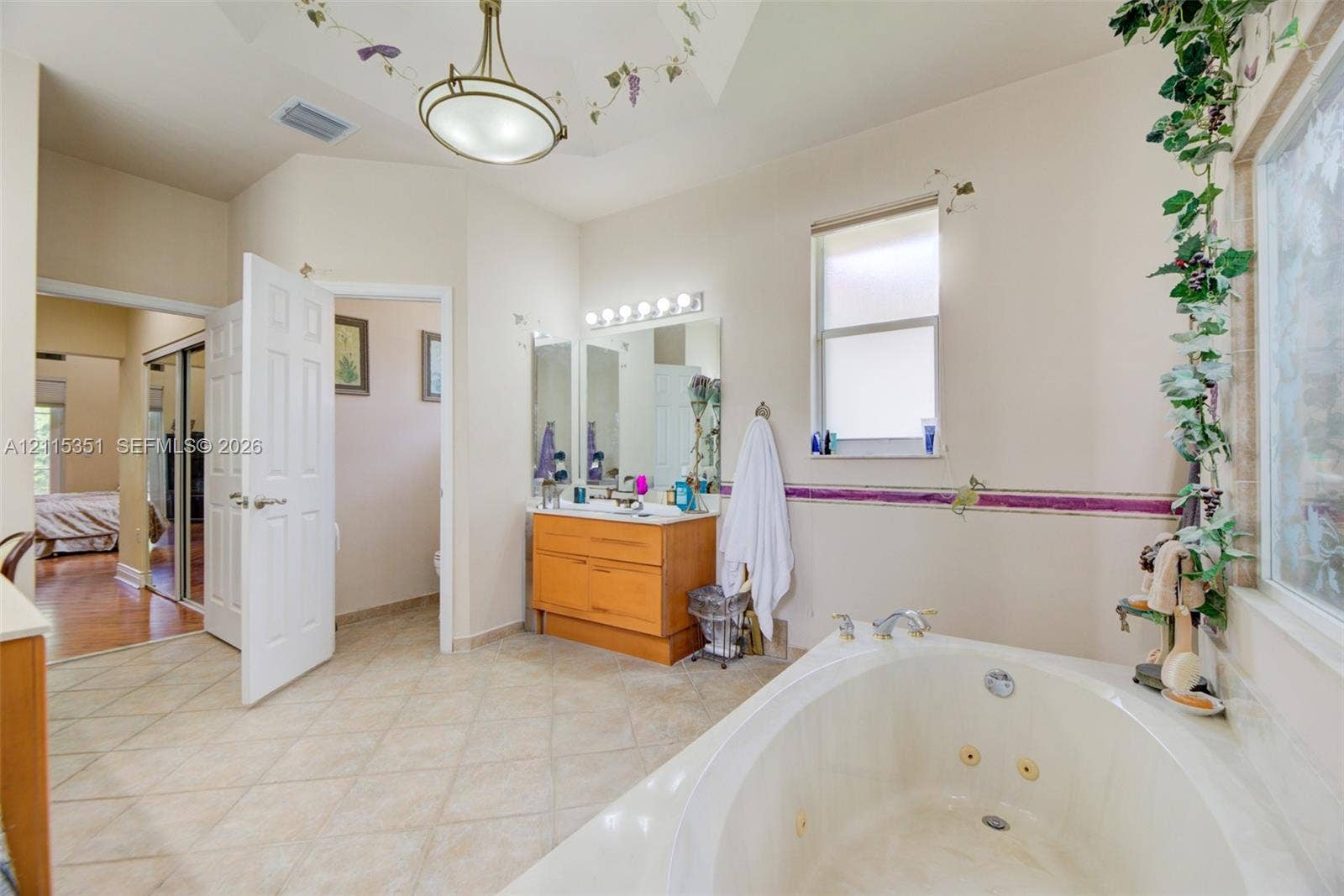 13845 NW 20th Street, Pembroke Pines, FL 33028 Bathroom featuring a jetted soaking tub, wood-finish vanity, tiled flooring, multi-light wall fixture, and vaulted ceiling with a decorative pendant light