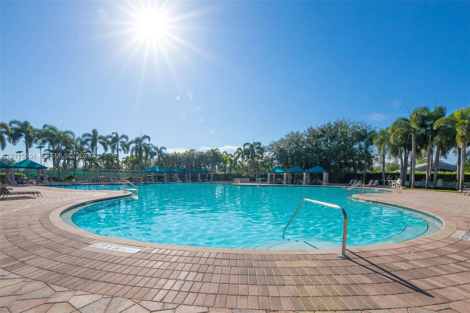 13845 NW 20th Street, Pembroke Pines, FL 33028 In-ground swimming pool featuring a brick paver surround, metal entry rails, and mature palm tree landscaping