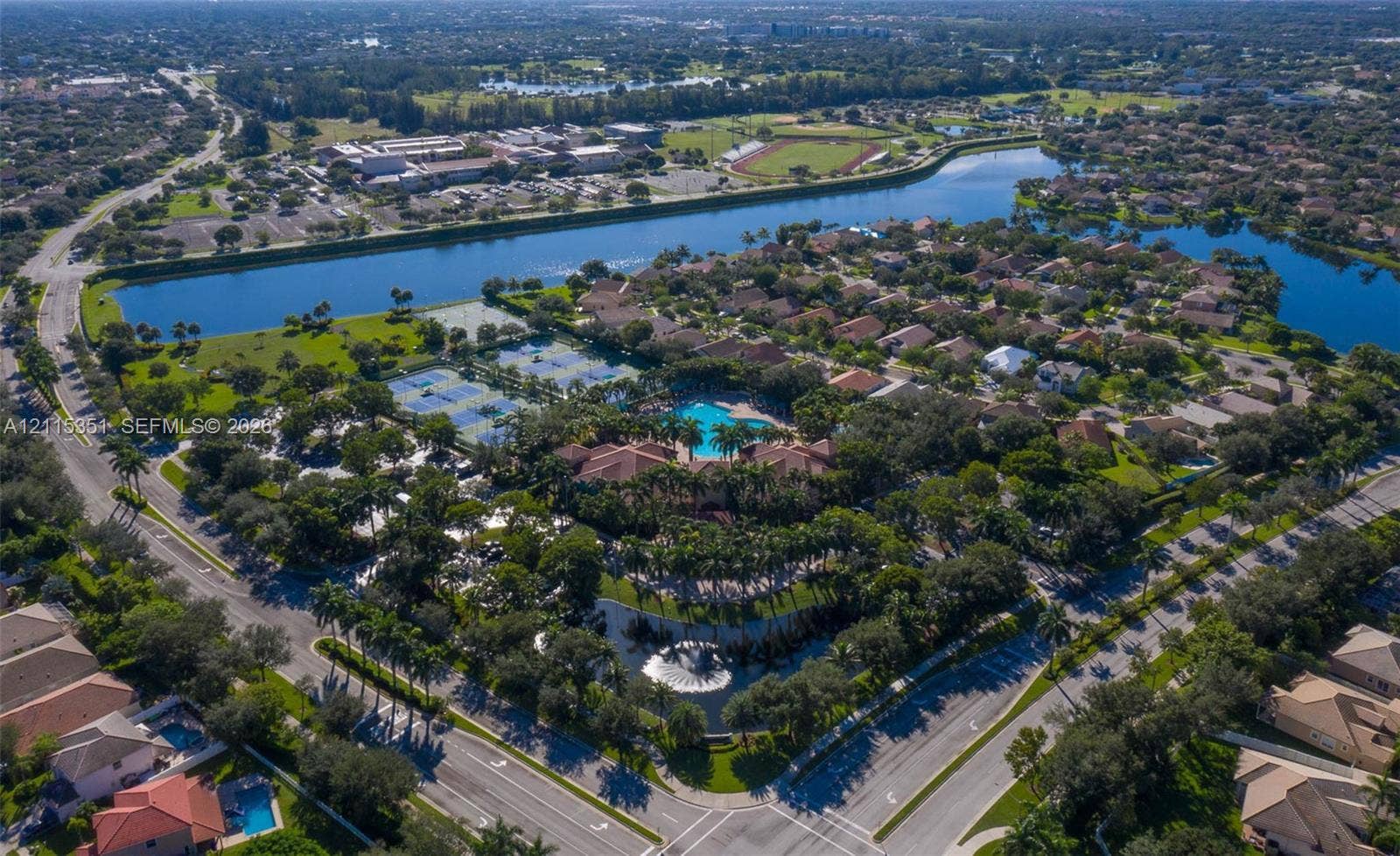 13845 NW 20th Street, Pembroke Pines, FL 33028 Aerial perspective of community featuring water frontage, tennis courts, an outdoor swimming pool, and mature landscaping