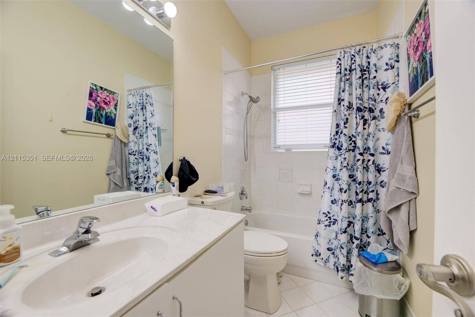 13845 NW 20th Street, Pembroke Pines, FL 33028 Bathroom featuring a solid-surface vanity countertop, an integrated sink with a chrome faucet, a wall-to-wall mirror, a porcelain tub-and-shower combination, and tiled flooring