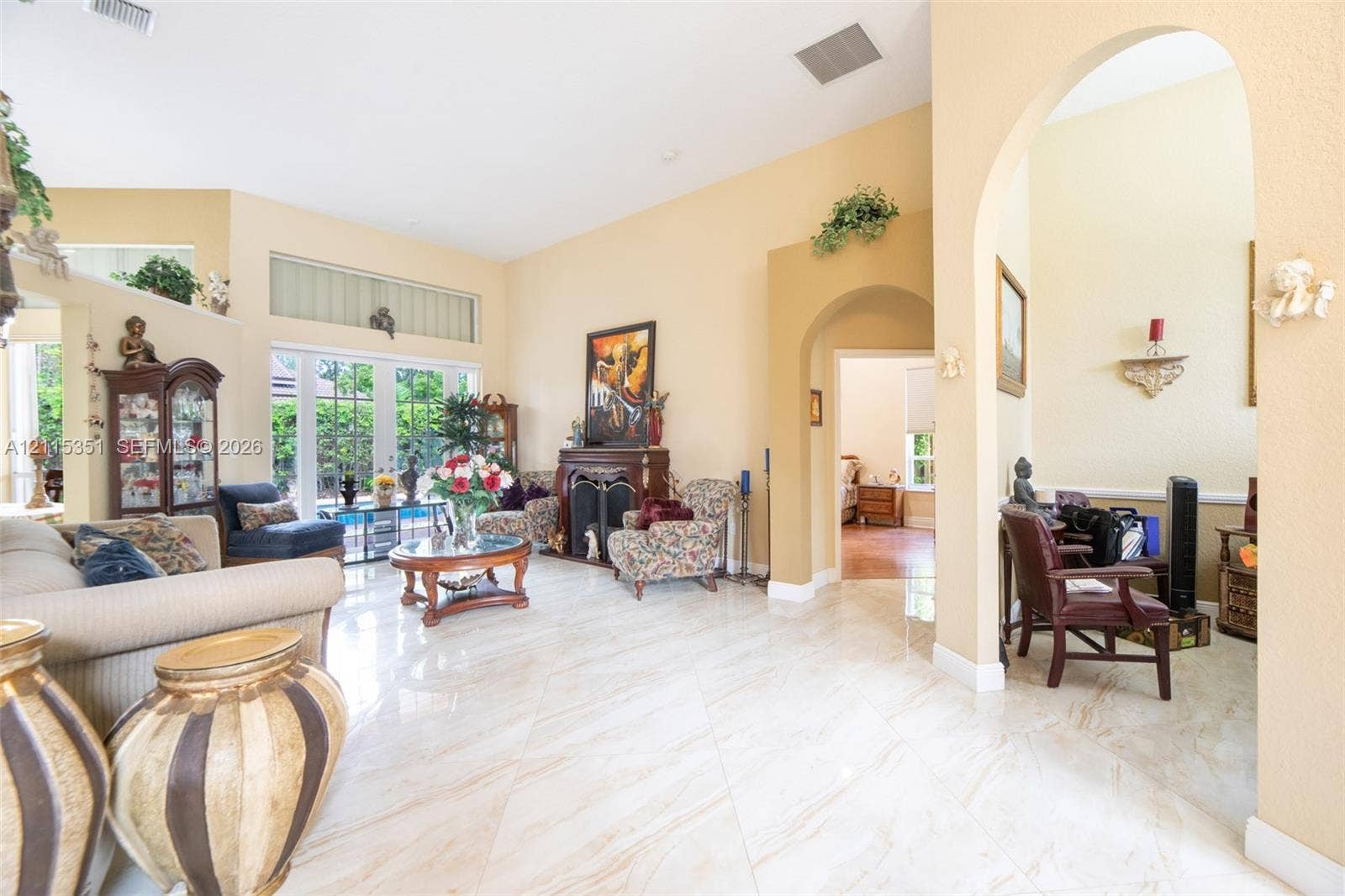 13845 NW 20th Street, Pembroke Pines, FL 33028 Living area featuring high ceilings, large-format tile flooring, a fireplace with a decorative mantel, arched entryways, and floor-to-ceiling windows