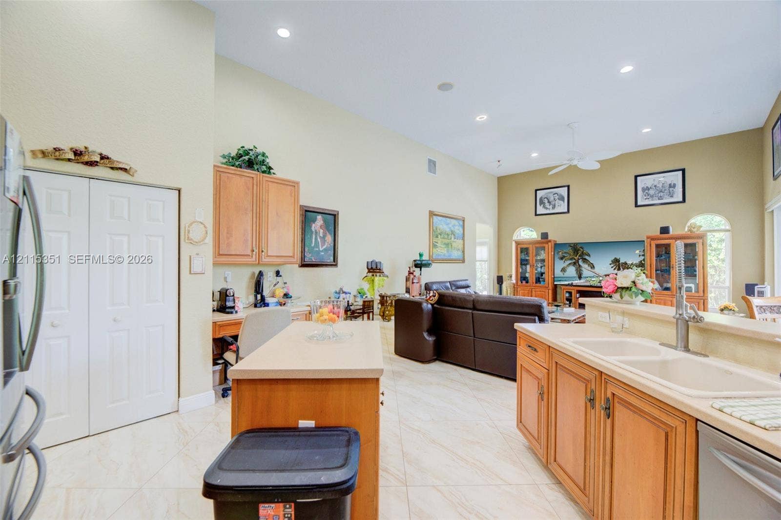 13845 NW 20th Street, Pembroke Pines, FL 33028 Open-concept area featuring vaulted ceilings, tile flooring, wood cabinetry, a center island with countertop seating, and recessed lighting