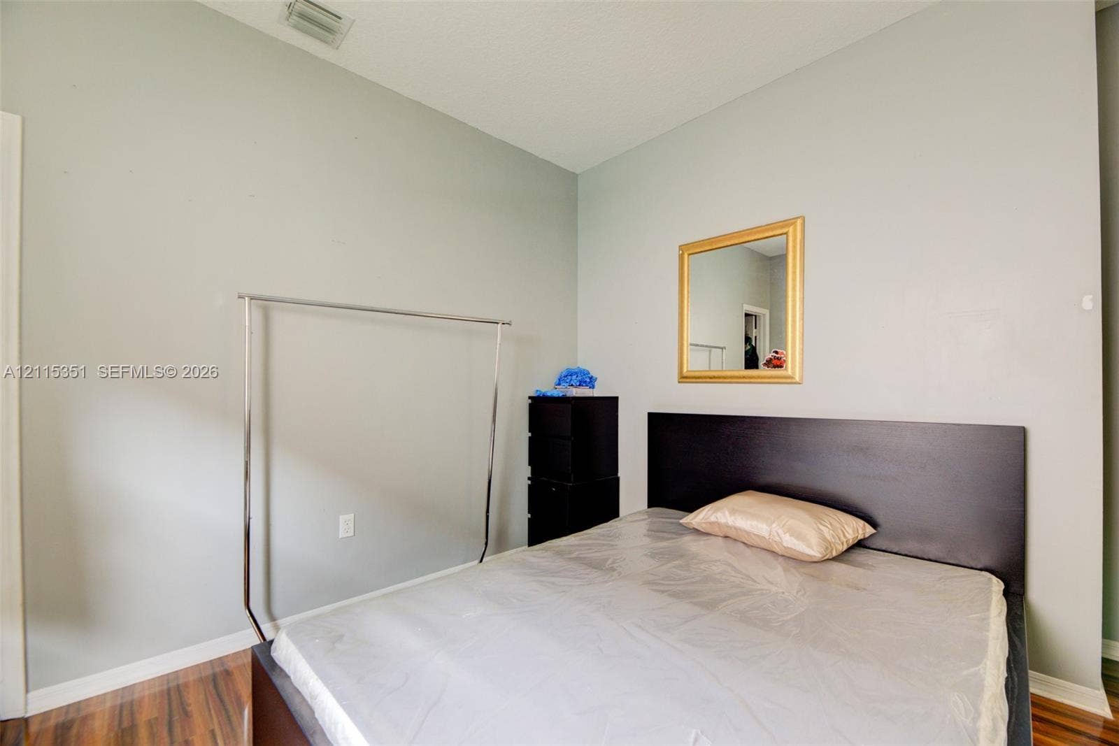 13845 NW 20th Street, Pembroke Pines, FL 33028 High-ceilinged room with wood-finish flooring and a wall-mounted mirror