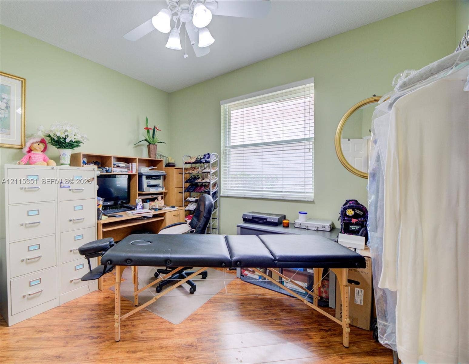 13845 NW 20th Street, Pembroke Pines, FL 33028 Room featuring wood-finish flooring, a ceiling-mounted light fixture with four glass shades, and a single-pane window with horizontal blinds