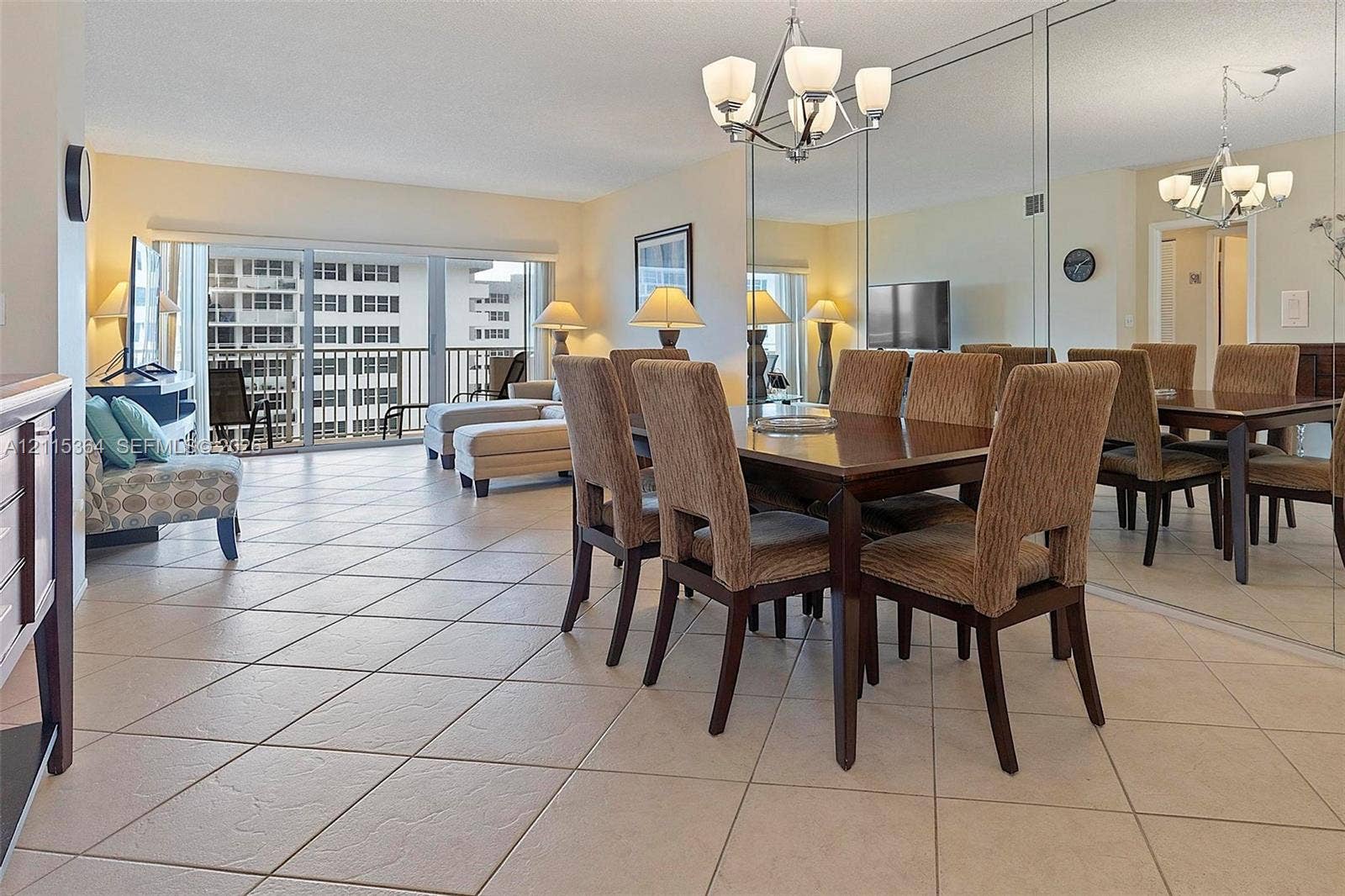 1980 S Ocean Drive, #20A, Hallandale Beach, Hallandale Beach, FL 33009 Open-concept dining area featuring large-format diagonal tile flooring, floor-to-ceiling mirrored wall accents, and an overhead multi-arm chandelier