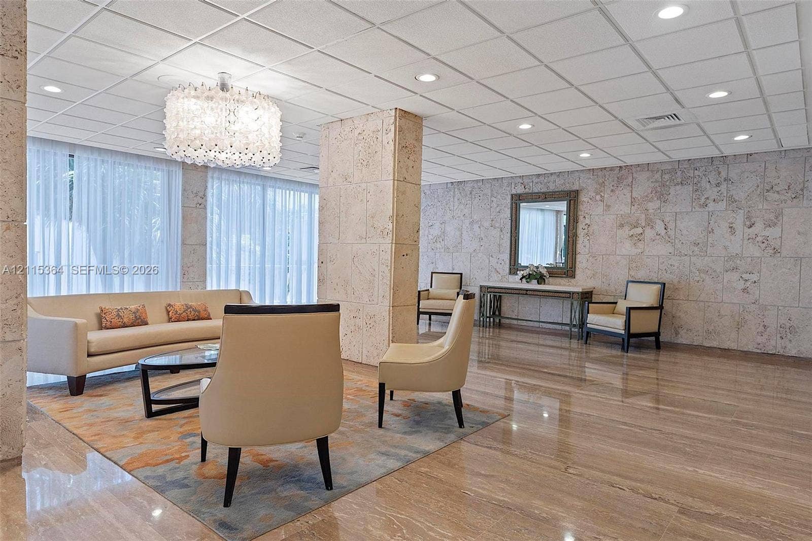 1980 S Ocean Drive, #20A, Hallandale Beach, Hallandale Beach, FL 33009 Polished stone flooring, textured stone wall cladding, a decorative chandelier, recessed ceiling lighting, and floor-to-ceiling sheer window coverings