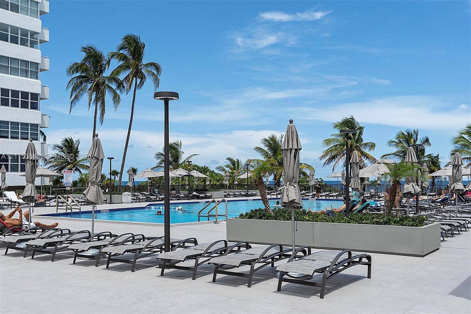 1980 S Ocean Drive, #20A, Hallandale Beach, Hallandale Beach, FL 33009 Swimming pool area featuring expansive stone-tile decking, integrated concrete planters, and exterior lighting fixtures