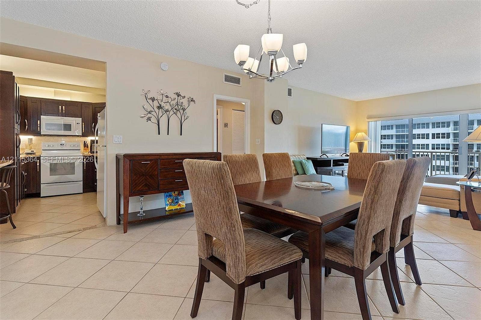 1980 S Ocean Drive, #20A, Hallandale Beach, Hallandale Beach, FL 33009 Open concept area featuring large-format ceramic tile flooring, a multi-arm chandelier, and a kitchen with dark-toned cabinetry and white appliances